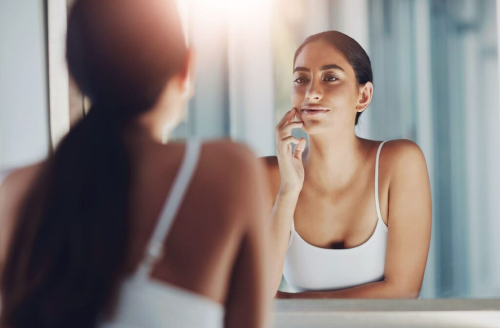 Person touching their skin in the mirror.