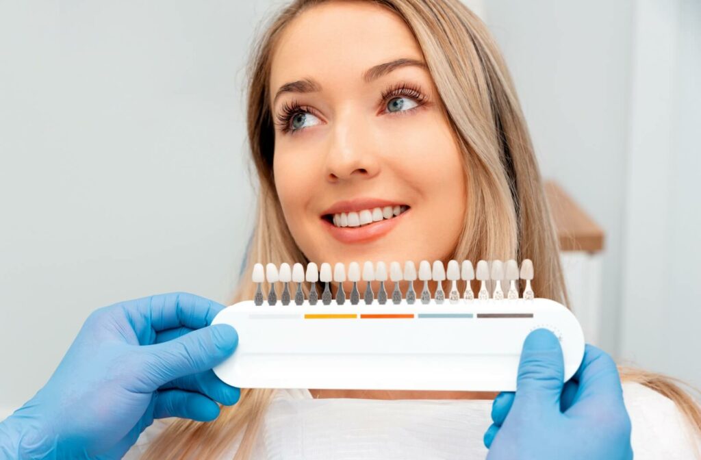 Dentist holding up different veneer shades, up close to a patient.