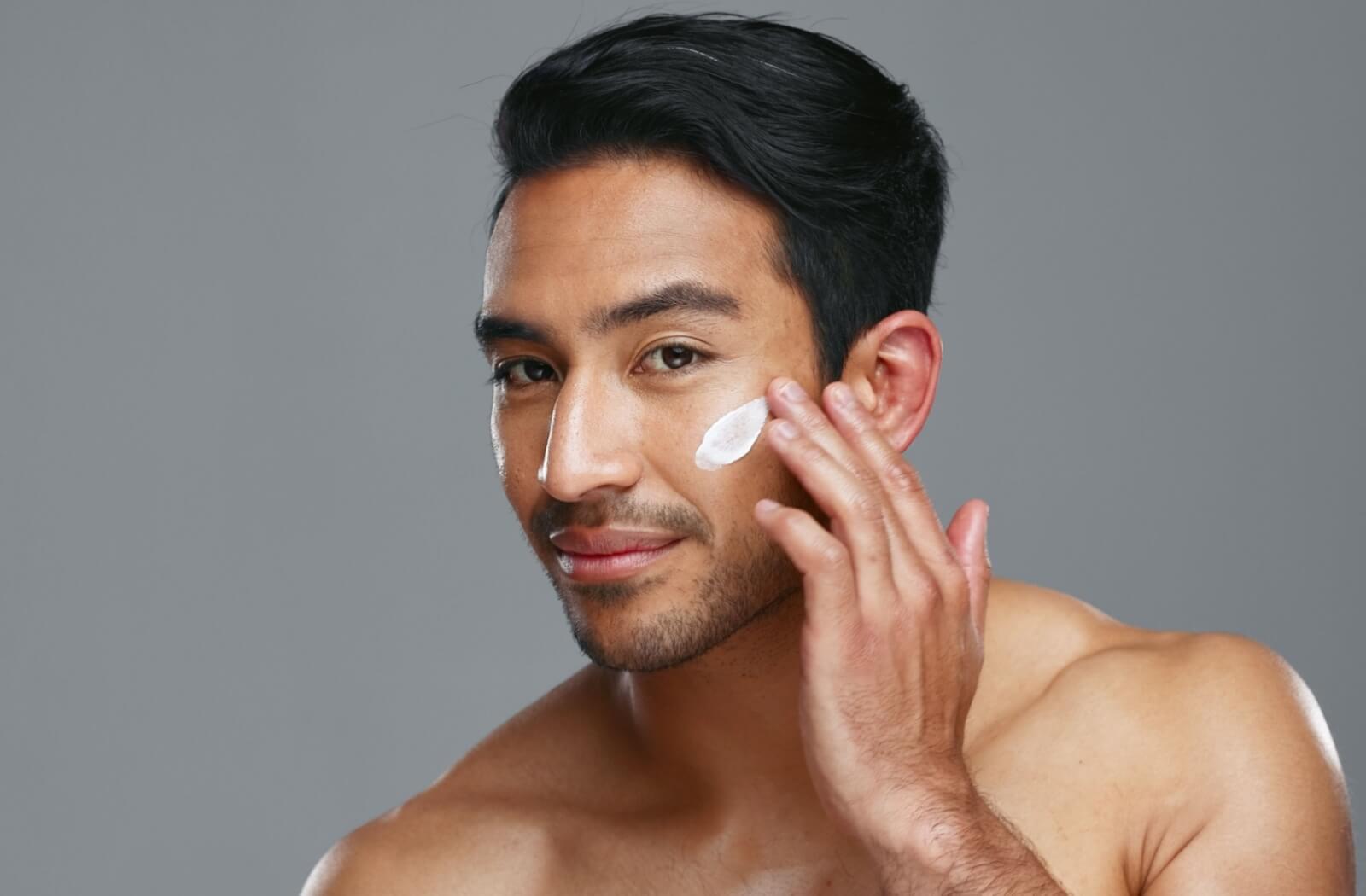 A smiling adult applies a nourishing face cream.