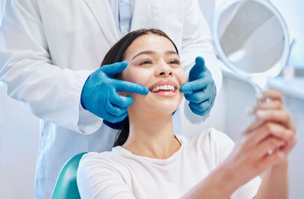 A patient holds a mirror to admire the final results of their smile makeover.